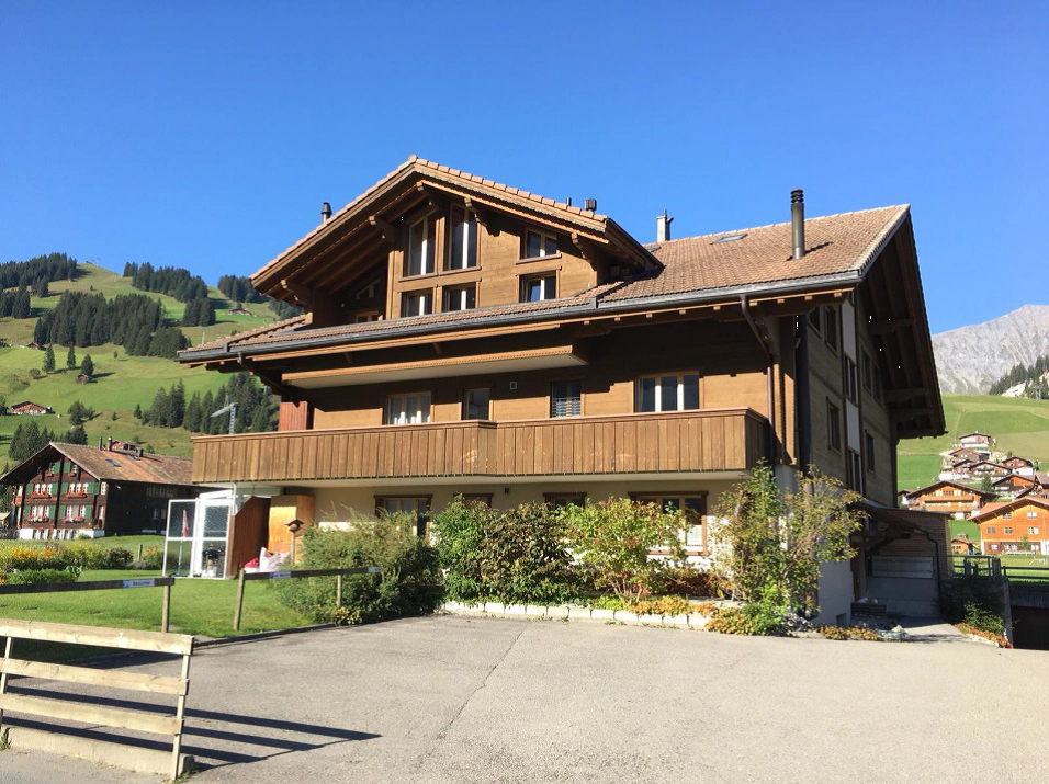 Traditionelles Chalet-Mehrfamilienhaus vor Alpenkulisse